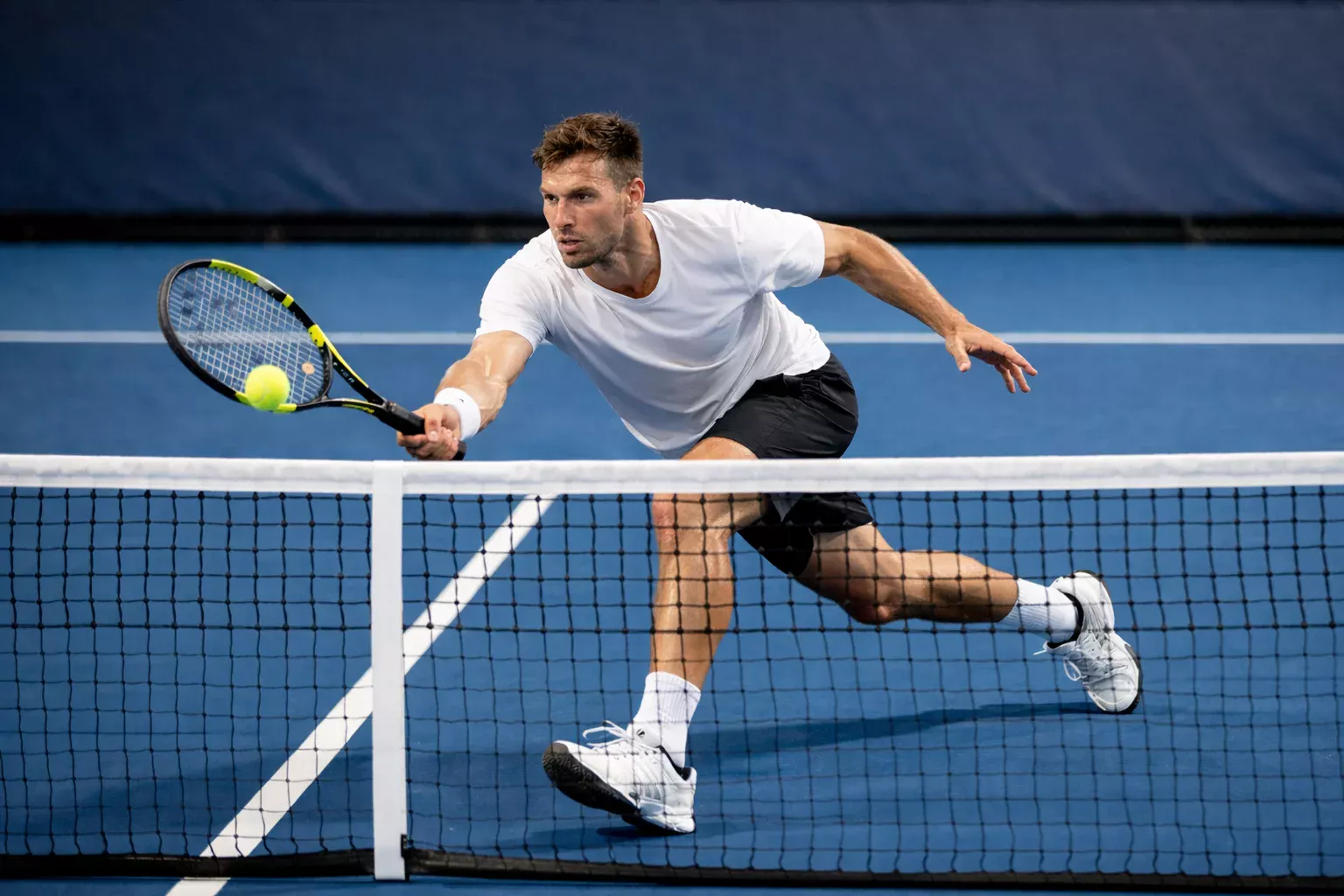 Tennisser in aanvallende positie bij het net tijdens een rally