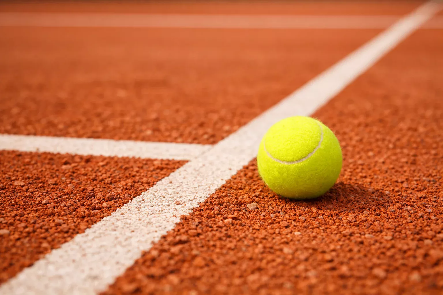 Close-up van een gravelcourt met tennisbal en witte lijnen op het rode zand